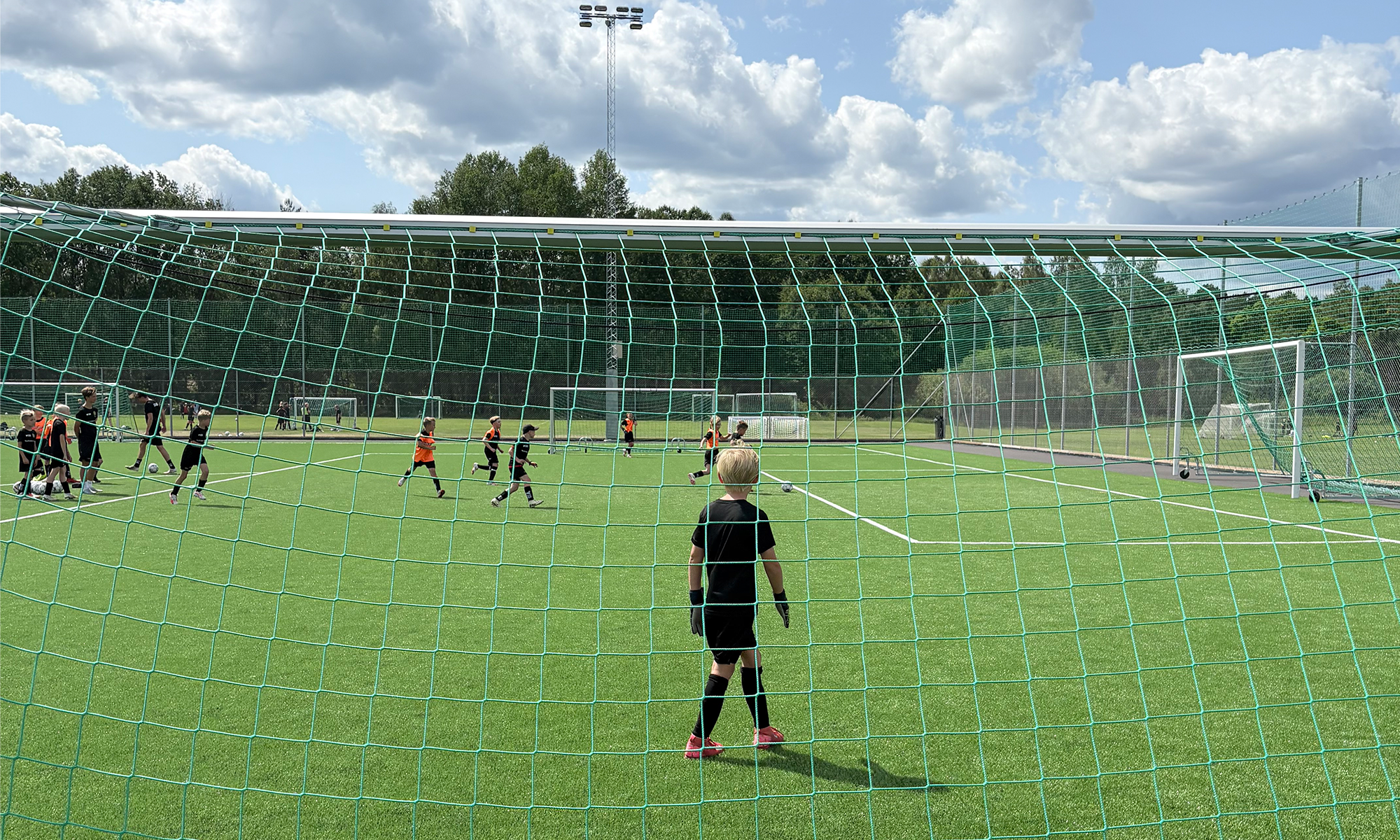 Barnen spelar fotboll på fotbollsplanen.