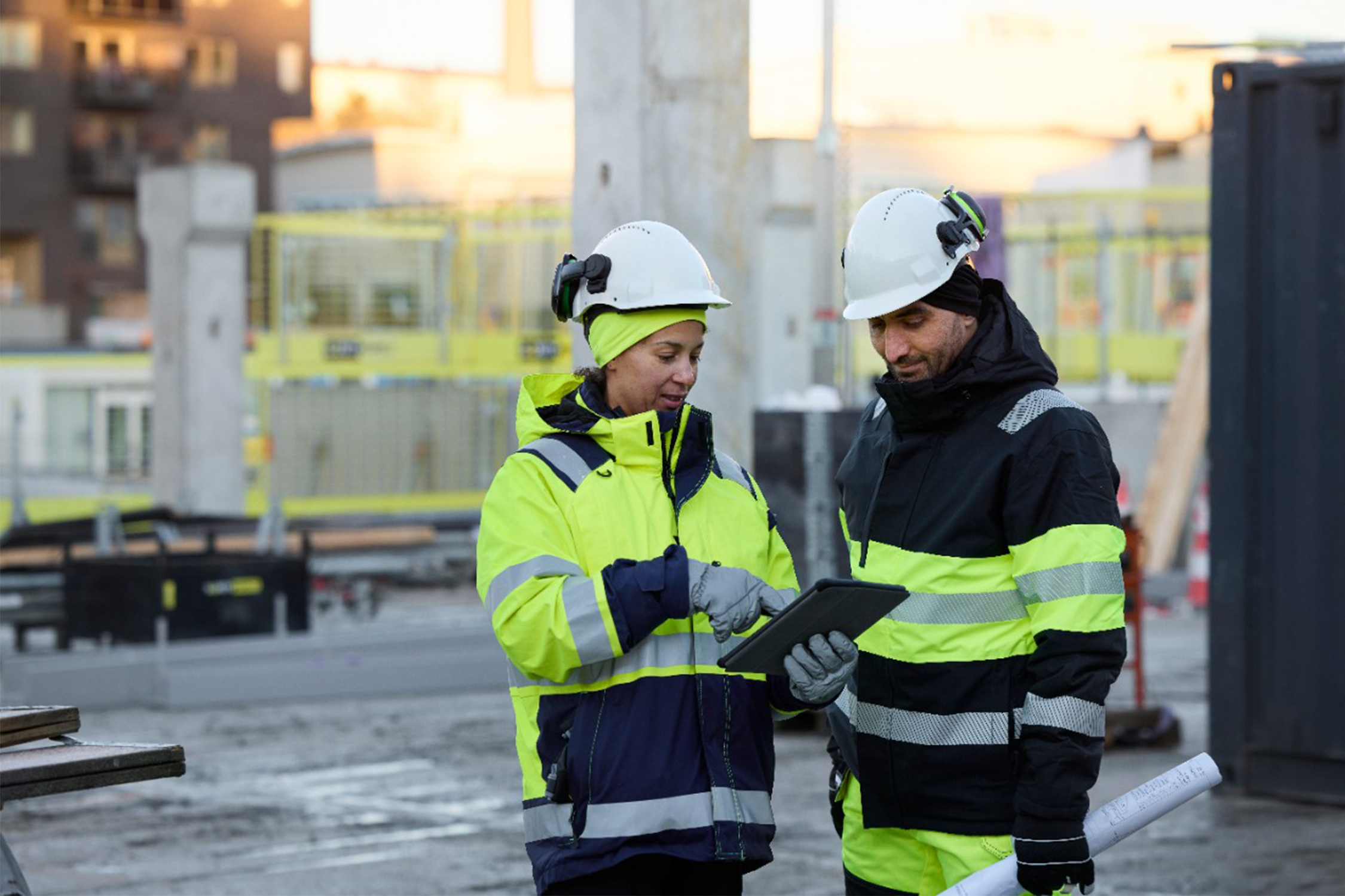 Två byggarbetare som står vid en byggarbetsplats och planerar.